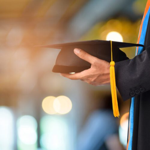 Graduation take a black yellow tassel in front of bokeh blurry background.